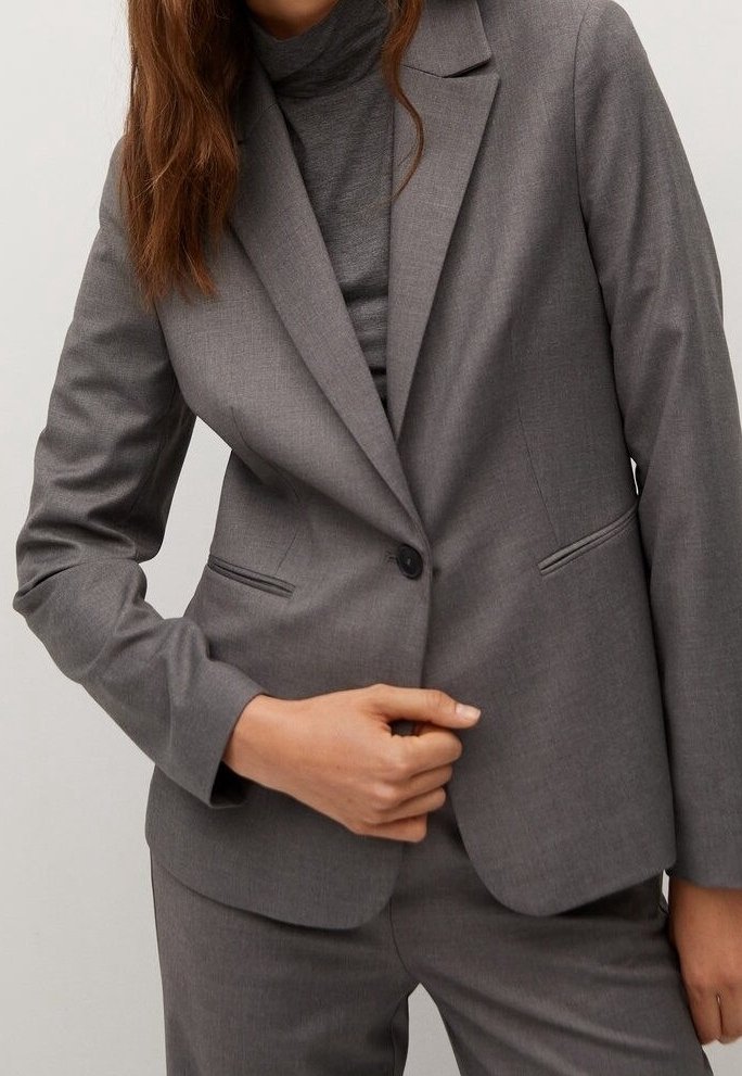 Grijze op maat gemaakte blazer met een enkele knoopsluiting, notch revers, twee voorzakken en een subtiele textuur. Draagt over een bijpassend fitted top.