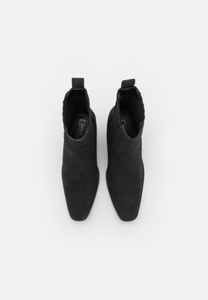 Bottines noires à bout pointu, en daim texturé, avec une languette à l'arrière et des accents côtelés.