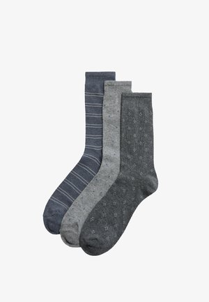 Tres pares de calcetines en varios tonos de gris: uno con rayas gris claro, uno con puntos azules y uno con un patrón de puntos texturizados.