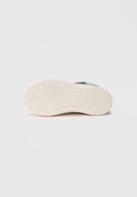 Tennisejalatsi tallal on tekstuuriga valge kumm ja hele roosa aksent. Disainis on reljeefne logo ja ümmargune mustri muster.