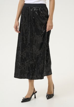 Kvinde iført sort midinederdel med palietter, sort elastisk talje og sorte spidse slingback hæle med små sløjfer.