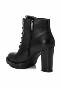 Botines negros de tacón alto con un acabado de cuero suave, cordones en la parte delantera, cremallera lateral y suela de plataforma con relieve.