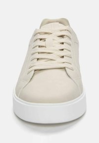 Beige tennarit, joissa on sileä nahkapinta, klassinen nauhakiinnitys ja paksu valkoinen kumipohja. Minimalistinen estetiikka ilman ylimääräisiä kuvioita.