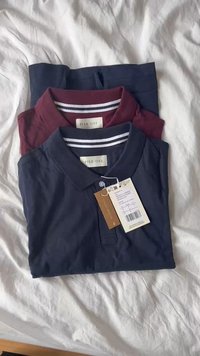 Zwei gefaltete Poloshirts: eines in Marineblau, das andere in Burgunderrot. Beide verfügen über einen Kragen, kurze Ärmel und ein Etikett. Strukturierter Baumwollstoff mit Streifenakzenten.