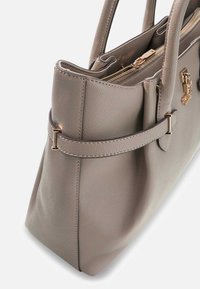 Szara torba shopper ze skóry o wyraźnie zarysowanym kształcie, z górnym zamkiem błyskawicznym i złotymi akcentami metalowymi. Posiada przeszycia dekoracyjne oraz boczny pasek.