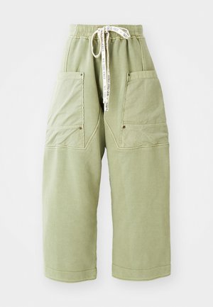 Lichtgroene wijde broek met grote voorzakken, elastische tailleband en witte trekkoord met de tekst "WE THE FREE".
