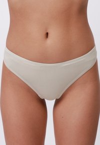 Világos bézs pamut bikini alsó, sima textúrával, alacsony derékkivágással és minimális varrási részletekkel; nincsenek látható minták vagy díszítések.