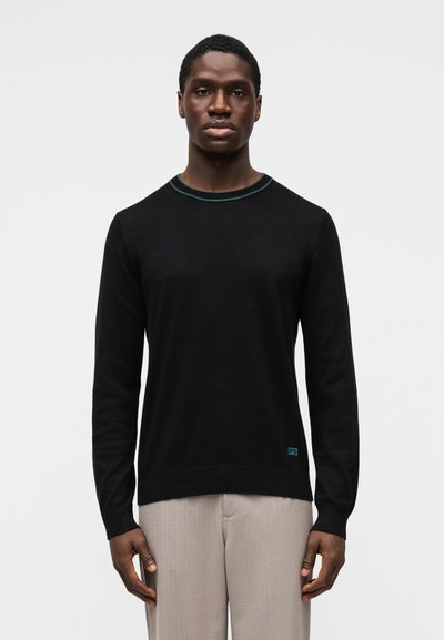 Pull noir à manches longues avec un col rond et un bord turquoise. Confectionné dans un tissu lisse, avec un petit logo en bas à gauche.
