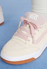 Roze i kremasti suede tenisice s bijelom gumom na potplatu i smeškim gumiranim donjim dijelom. Značajke uključuju vezice, podstavljeni jezik i detalj pruge sa strane.