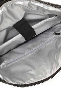Intérieur d'un sac en tissu noir avec doublure argentée, comportant un compartiment central, une sangle noire et une poche zippée pour un rangement sécurisé.