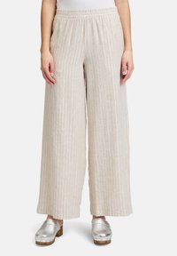 Beżowe spodnie o szerokich nogawkach z pionowymi białymi paskami, z elastycznym pasem. Tkanina jest lekka i przewiewna.