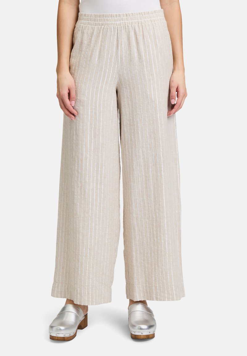Beżowe spodnie o szerokich nogawkach z pionowymi białymi paskami, z elastycznym pasem. Tkanina jest lekka i przewiewna.