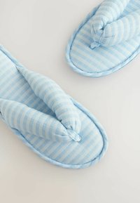 Blåternet stofslipser med et blødt, polstret design, der har en twist-detalje ved tæerne og runde kanter.