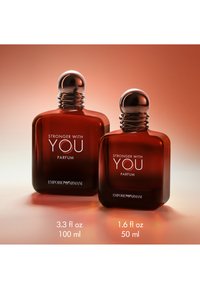 Twee amberglazen parfumflessen met ronde metalen doppen, gelabeld "Stronger With You Parfum" van Emporio Armani, in maten van 100 ml en 50 ml.