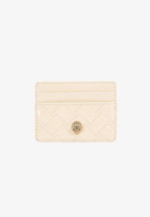 Porte-cartes en cuir crème avec un motif matelassé, orné d'un détail en métal doré au centre. Trois emplacements pour cartes. Texture lisse.