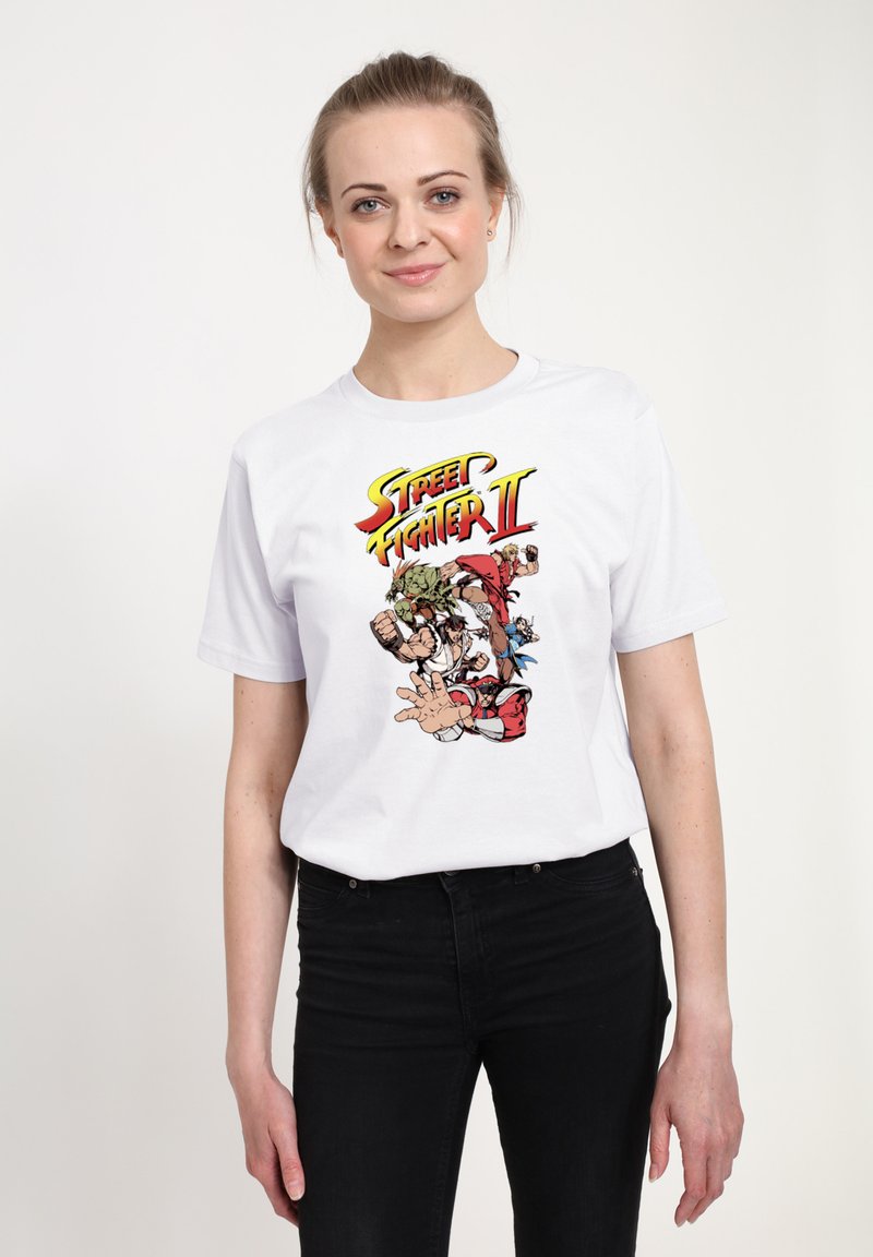 Bílý bavlněný tričko s grafikou "Street Fighter II" v živých barvách, zobrazující ikonické postavy v akčních pozicích. Krátké rukávy, kulatý výstřih.