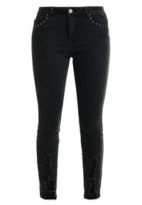 Jeans skinny de mezclilla negra con detalles desgastados en las piernas inferiores y tachuelas plateadas en los bolsillos frontales. Cierre clásico con botón.