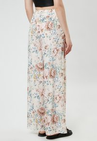 Floral wide-leg trousers in light fabric with a cream background, featuring pink and blue flowers and a relaxed fit with an elastic waistband.