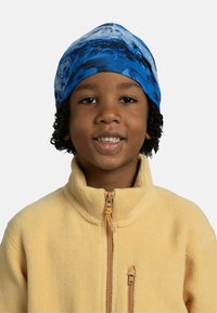 Blue and white patterned headband made of stretchy fabric, worn by a child with curly hair, paired with a yellow fleece jacket.