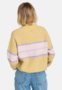 Gehaakte trui in geel met roze en lavendel strepen, met een boxy fit en geribde textuur. Ronde halslijn en verlaagde schouders.