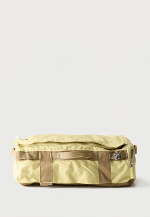 Lichtgele rechthoekige duffeltas met beige hengsels, een ritssluiting bovenaan en een kunststof gesp aan de voorkant, geplaatst op een effen witte achtergrond.