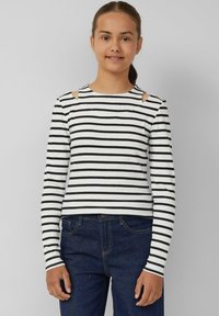 Gestreiftes Langarm-T-Shirt in Weiß und Schwarz, mit ausgeschnittenen Schulterdetails, gerippter Textur und taillierter Passform. Kombiniert mit dunkelblauen Jeans.