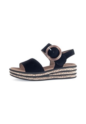Black sandal with a round wooden accent and adjustable strap. Features a textured, layered sole with black and light brown stripes.