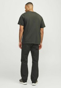Dark gray cotton t-shirt and black pants. T-shirt features a crew neck and short sleeves; pants are straight leg with pockets. Footwear shows patterned design.