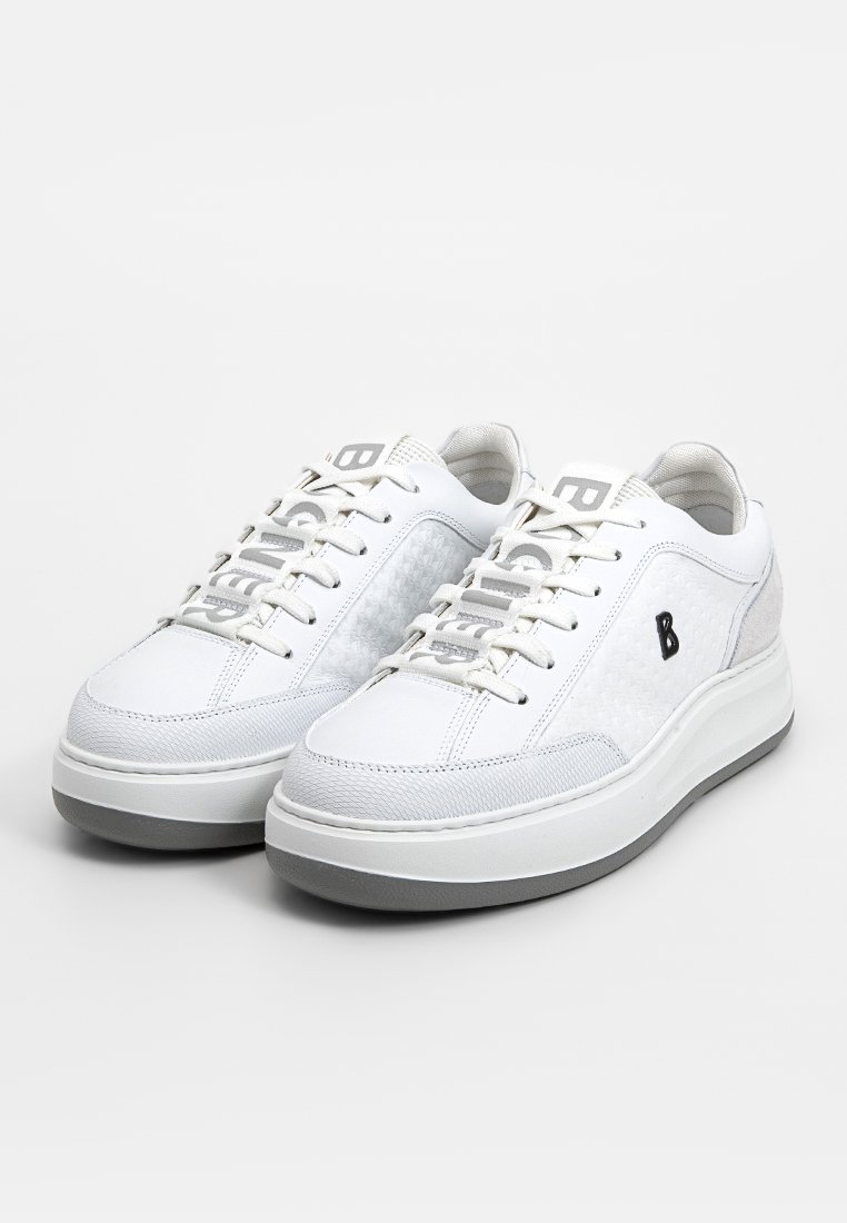 Ein Paar weiße Low-Top-Sneaker mit strukturierten Seiten, grauen Sohlen und schwarzem "B"-Logo an der Außenseite, präsentiert auf einem weißen Hintergrund.