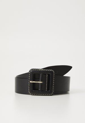 Ceinture en cuir noir avec grande boucle carrée comportant des coutures blanches et une épingle dorée, roulée et posée sur une surface blanche.