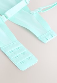 Türkiissinine valjas reguleeritavate rihmade, võrgust detailide ja takjapael kinnitustega, kuuel aasaga taga kindlaks kinnitamiseks.