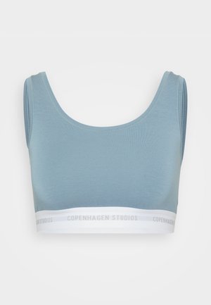 Svijetloplava tkanina uska majica s širokim naramenicama i bijelom elastičnom trakom s tekstom "COPENHAGEN STUDIOS" u sivoj boji. Glatka tekstura.