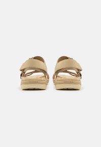 Beige sandaler med justerbare stropper, teksturert fotseng, polstret såle og fargerike detaljer på stroppene. Merkeetikett synlig.
