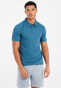 Korte mouw polo in teal, met een kraag en een drieknops sluiting. Gemaakt van een gestructureerde stof.