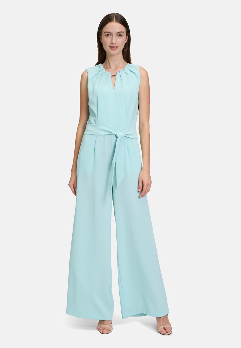 Mintgrön ärmlös jumpsuit med volangkrage, nyckelhålsutskärning och bälte i midjan, med vida byxben och slät tygtextur.