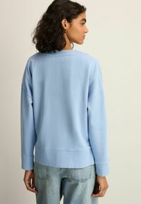 Lyseblå sweatshirt med ribbede manchetter og kant, oversized pasform, lavet af en bomuldsblanding, med rund halsudskæring og sænket skuldre.
