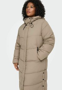 Bēša garā polsterētā jaka ar kapuci, aprīkota ar rāvējslēdzēju priekšpusē, regulējamām auklām, sānu kabatām un spiedpogām gar apakšmalu.