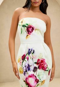 Strapless jurk van lichtgewicht stof, met een witte basis en een levendige bloemenprint in roze, rood en paars, met geplooide details bij de taille.