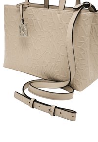 Borsa tote beige realizzata in materiale embossato con un motivo logo ripetuto. Presenta manici doppi e una tracolla staccabile con dettagli neri.