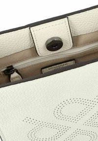 Borsa a mano in pelle bianca con superficie testurizzata, chiusura a scatto magnetico e tasca interna con zip foderata in beige. Design decorativo perforato visibile.
