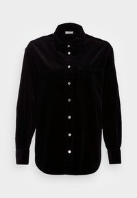 Camicia in cotone a coste nera con design a bottoni, maniche lunghe, tasca sul petto e bottoni argentati. Tessuto testurizzato con righe verticali.