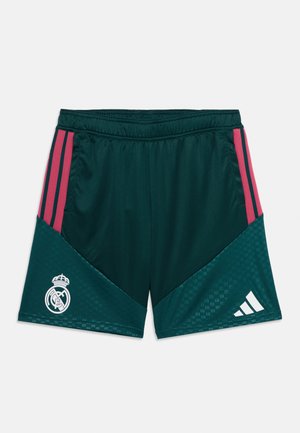 Pantalones cortos deportivos verde oscuro con rayas rosas en los costados, logo de Real Madrid en la pierna izquierda y logo de Adidas en la pierna derecha.