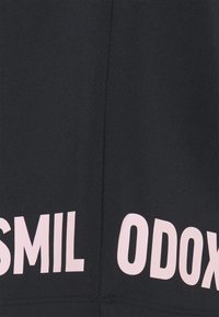 Zwarte stof met een gladde textuur en grote roze tekst waarop in vetgedrukte letters "SMIL" en "ODOX" staat.