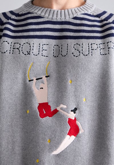 Hallhalli halliga, millel on tumesinisest triibulisest kraest. Omab tikanditud tsirkuse stseeni punastes kostüümides tegelastega. Üleval on tekst "CIRQUE DU SUPER."