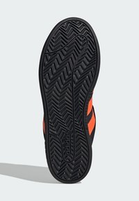 Suola nera di scarpa Adidas con motivo a zig zag e lati superiori arancioni su sfondo grigio chiaro.