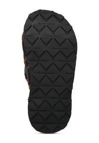 Black rubber sole with a textured surface featuring triangular patterns and branding, tapering to a rounded toe and slight side curvature.