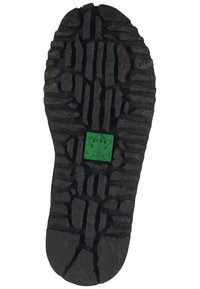 Black rubber shoe sole with pronounced tread pattern. Features a green frog emblem in the center. Texture is rugged and durable.