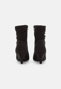 Černé nubukové kotníkové boty s nařasením, zipem na zadní části a jednoduchým, zúženým podpatkem. Hladký povrch po celém obvodu.