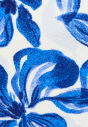 Close-up van een blauw bloemenpatroon met donkere en lichte blauwe bloemblaadjes op een gestructureerde witte stoffen achtergrond.