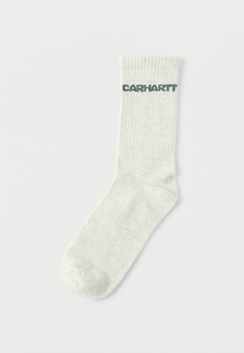 Světlě šedá žebrovaná ponožka s kontrastním tmavě zeleným logem "Carhartt" nahoře. Vyrobená z měkkého, texturovaného materiálu.